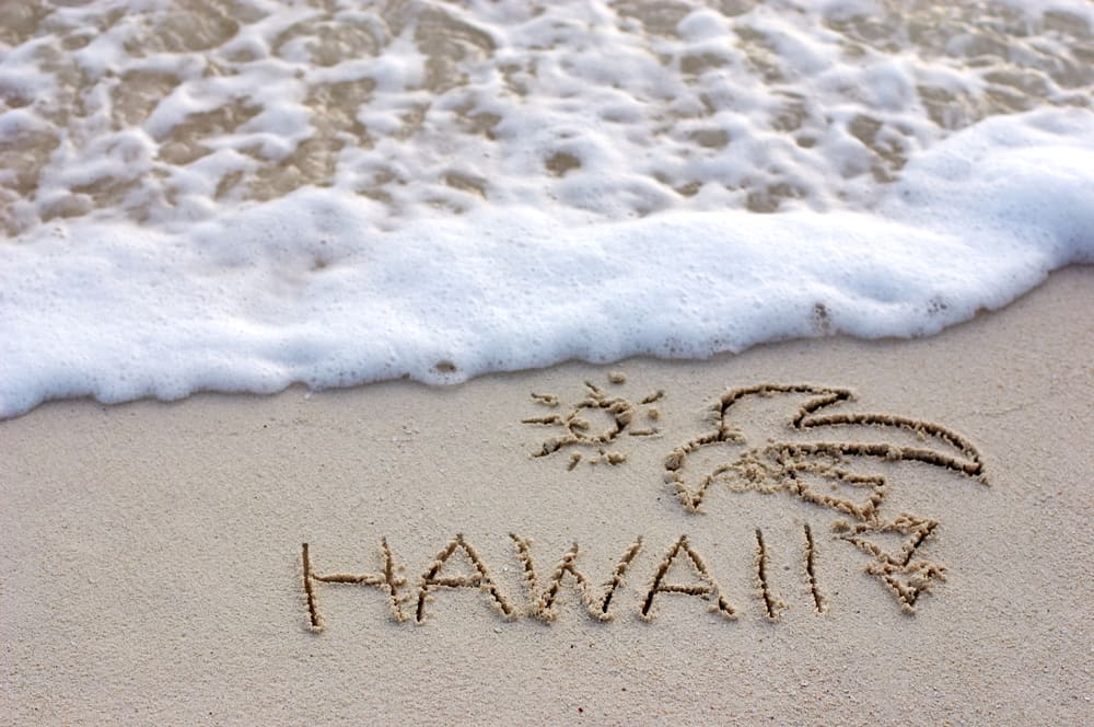 the word Hawaii written on a beach