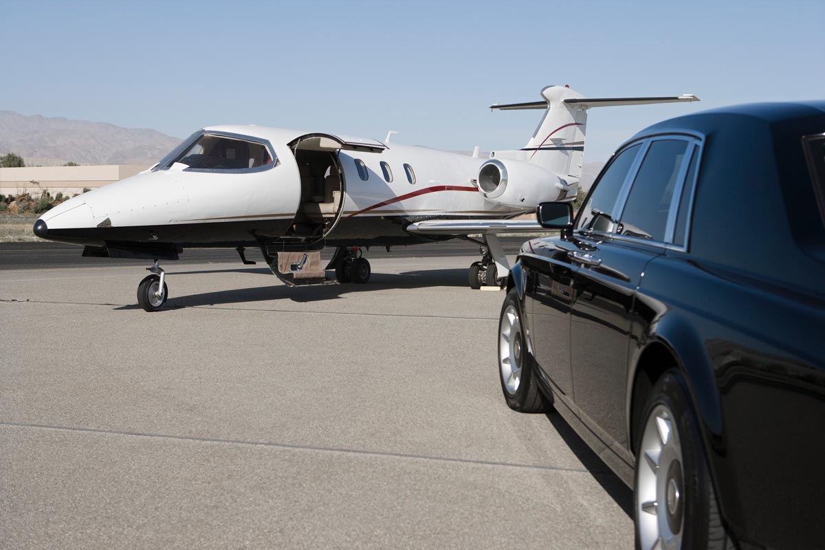 A luxury car parked at a private jet ready to take off